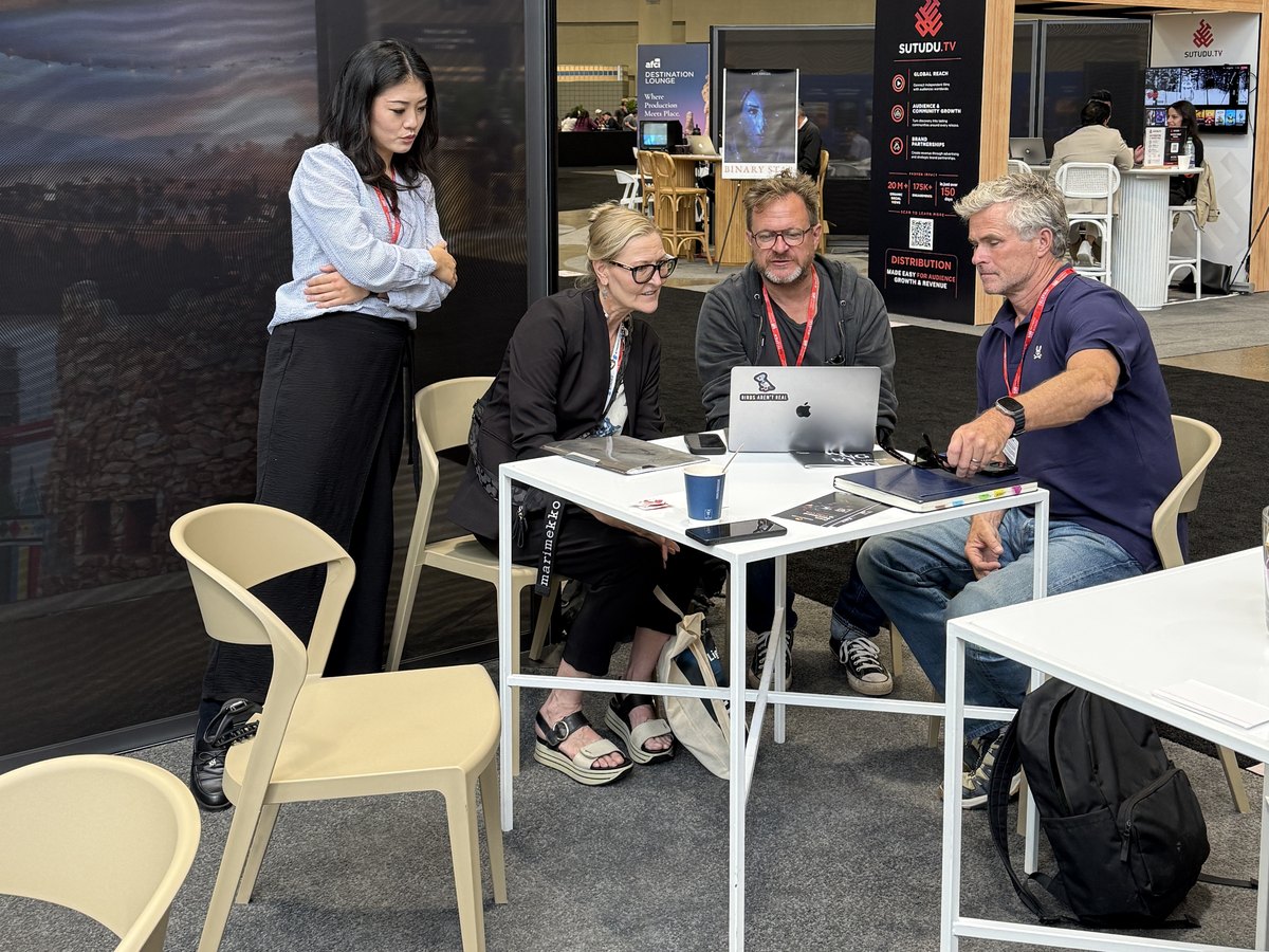 Four people meeting around a table with a laptop at the Moonlite Labs booth
