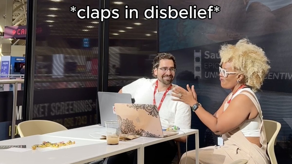 A Moonlite Labs team member and a creator talking over a laptop at the booth, with the caption claps in disbelief