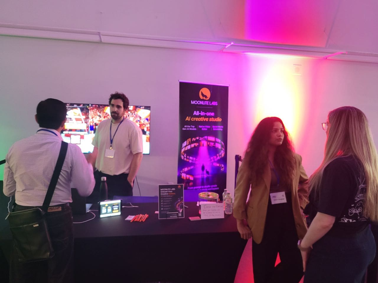 Visitors talking with the Moonlite Labs team at the exhibition booth under pink and purple lighting at VRTO 2026
